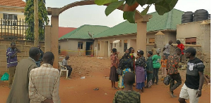 Residents and passersby look on at the rented house where three siblings died in a fire