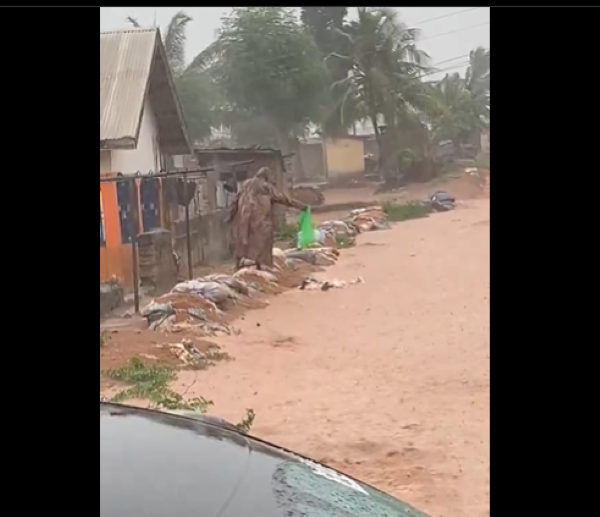 One of the residents is seen pouring refuse into the flowing water during the rain