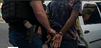 In this Sept. 3, 2018 photo, a plained clothed police officer escorts an handcuffed man
