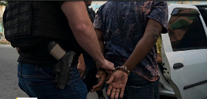 In this Sept. 3, 2018 photo, a plained clothed police officer escorts an handcuffed man