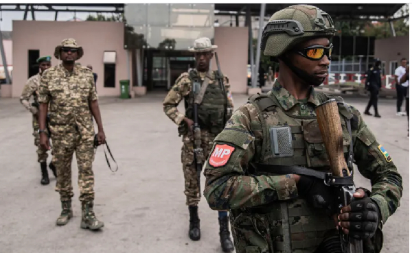 Members of the M23 movement stand guard for the convoy of FDLR) soldiers