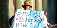 Activist Julius Kamau holds a placard reading 'End State Abductions Now' as he protests