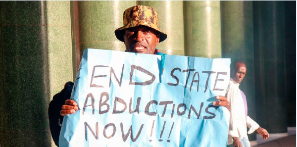 Activist Julius Kamau holds a placard reading 'End State Abductions Now' as he protests