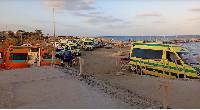 Rescuers and ambulance cars wait on the beach for possible survivors