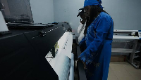 Oluwatosin and her husband, co-owners of a printing business, wait for the output of a printer