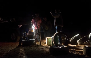 Young men fix a tyre in the dark at an all-night truck stop in Insuza
