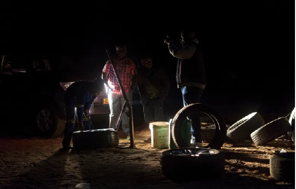 Young men fix a tyre in the dark at an all-night truck stop in Insuza