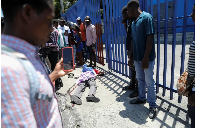 People look at the body of a man as rival gangs vie for control in Port-au-Prince, Haiti, on April 1