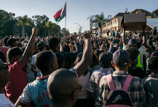 People cheer and hold banners as they gather for a rally outside City Hall in Antananarivo