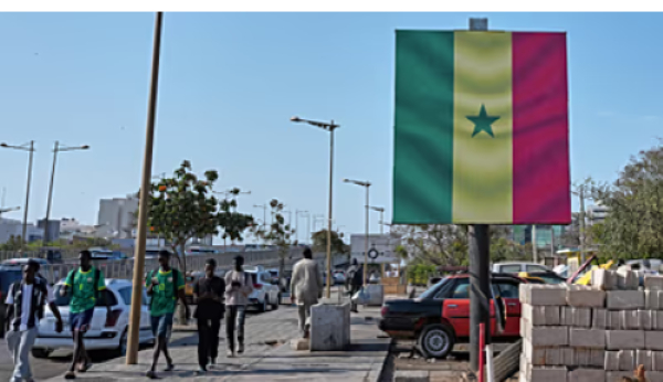 Pedestrians walk past a billboard with the Senegal flag in Dakar, Senegal