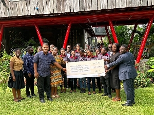 DEI and Fidelity Bank staff stand together, holding a dummy cheque with the beneficiary students.
