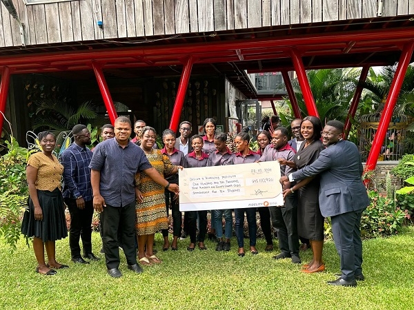 DEI and Fidelity Bank staff stand together, holding a dummy cheque with the beneficiary students.