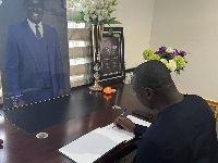 The Minister of Finance, Mohammed Amin Adam signing a book of condolence for John Kumah