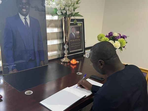 The Minister of Finance, Mohammed Amin Adam signing a book of condolence for John Kumah