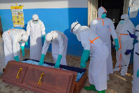 Medical staff in protective gear place an Ebola victim's body into a coffin at Bunia Hospital