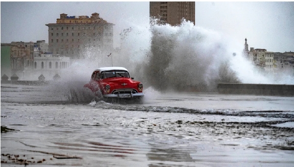 An old American car passes along the flooded Malecón esplanade in Havana, Cuba, on February 5