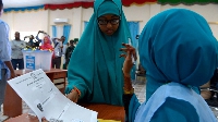 A polling agent (R) explains the voting procedure to a voter before she casts her ballot in Baidoa