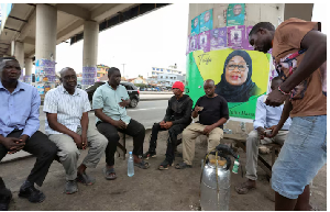 People Sit Under A Foot Bridge With An Electoral Campaign Poster .png