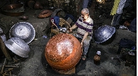 A coppersmith makes a vessel at a workshop in Cairo, Egypt, on August 13, 2023