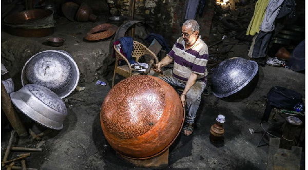 A coppersmith makes a vessel at a workshop in Cairo, Egypt, on August 13, 2023