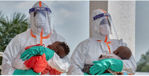 Congolese medical workers wearing PPE carry children  from Saint Nicholas Orphanage