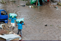 People carry sacks as they walk through floodwaters following heavy rainfall in Nairobi,April 28