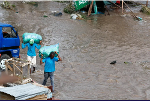 People carry sacks as they walk through floodwaters following heavy rainfall in Nairobi,April 28