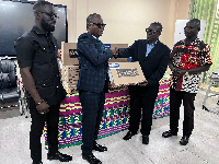 Joseph Kpemka presenting a laptop to one of the beneficiaries