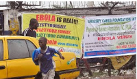 People pass by Ebola virus health warning signs, in the city of Monrovia, Liberia, Aug.  17, 2014