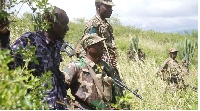 Uganda soldiers and police hide in a bush during a patrol