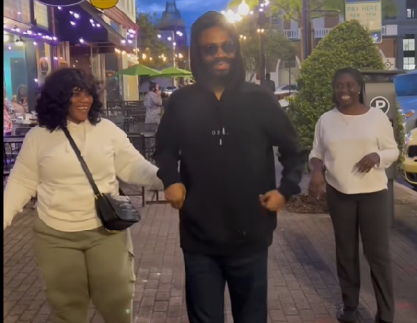 Kofi Adoma being cheered on by his wife and a relative during a walk