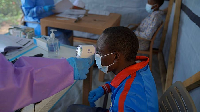 A health workers checks the temperature of a man before administering a dose of the Tumaini vaccine
