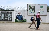 Pedestrians walk past an image of Ivorian businessman Tidjane Thiam