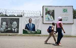 Pedestrians walk past an image of Ivorian businessman Tidjane Thiam