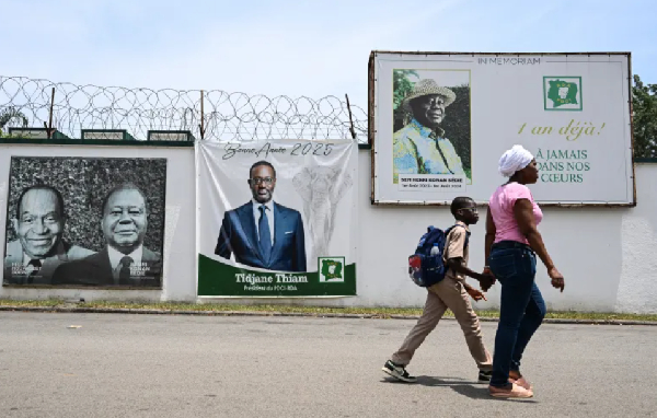 Pedestrians walk past an image of Ivorian businessman Tidjane Thiam