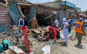 Plainclothes police officers and residents examine damage at the site of bomb explosion at a market