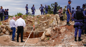 Police officers and private security personnel stand by the opening of a reformed gold mineshaft