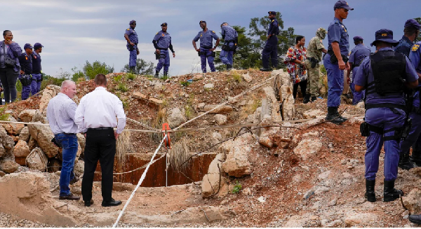 Police officers and private security personnel stand by the opening of a reformed gold mineshaft