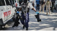 A police officer carries equipment seized from suspected kidnapper's car