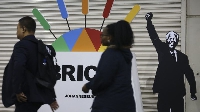 South Africans walk past one advertisement for one Brics summit wey feature one image of Mandela