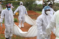 Forensic experts and homicide detectives carry the bodies of suspected members of a Christian cult