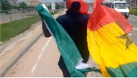 A man holding a Nigeria flag (left) and a Ghana flag (right)