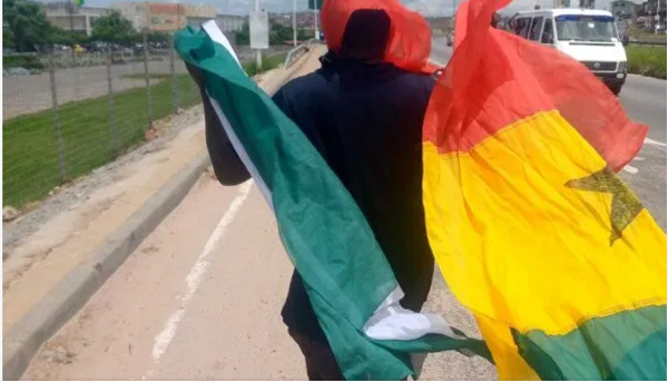 A man holding a Nigeria flag (left) and a Ghana flag (right)