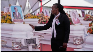 A mourner looks at a photograph of one of the 16 girls who died in the Utumishi Academy school fire