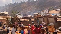 People stand at the site of school fire that killed several people in Bukavu