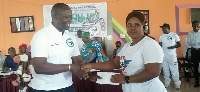 A lady receives a white envelope from Armah Kofi Buah