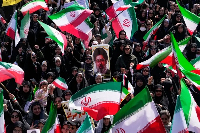 Women hold Iranian flags and a portrait of Supreme Leader Ayatollah Mojtaba Khamenei