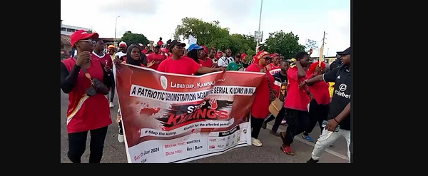 Some protestors clad in red attire and carrying a banner