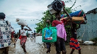 Displaced people in central South Sudan walk with their belongings in a flooded area