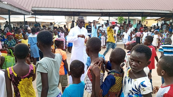 Very Reverend Father Stephen Amoah-Gyasi with some children in a photo